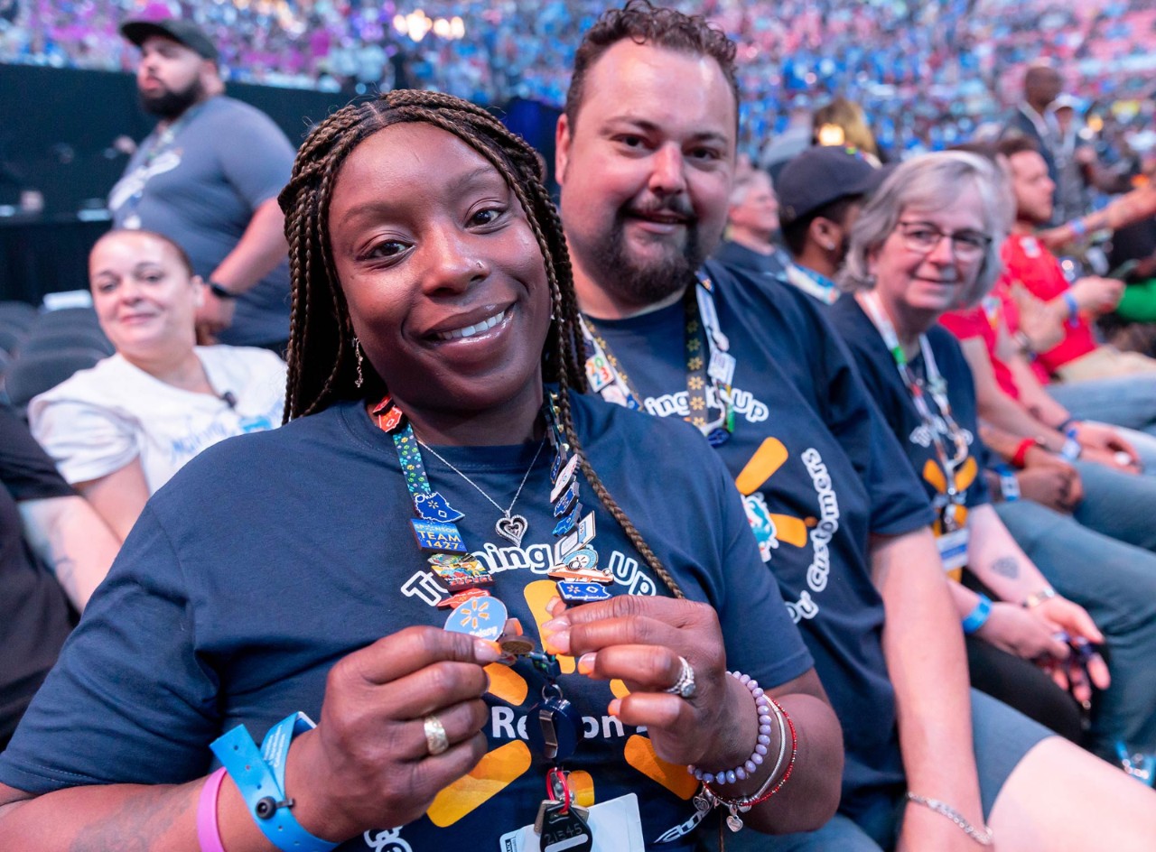 An associate smiles and holds up her lanyard that features several different Walmart-themed pins at Associates Week 2024.