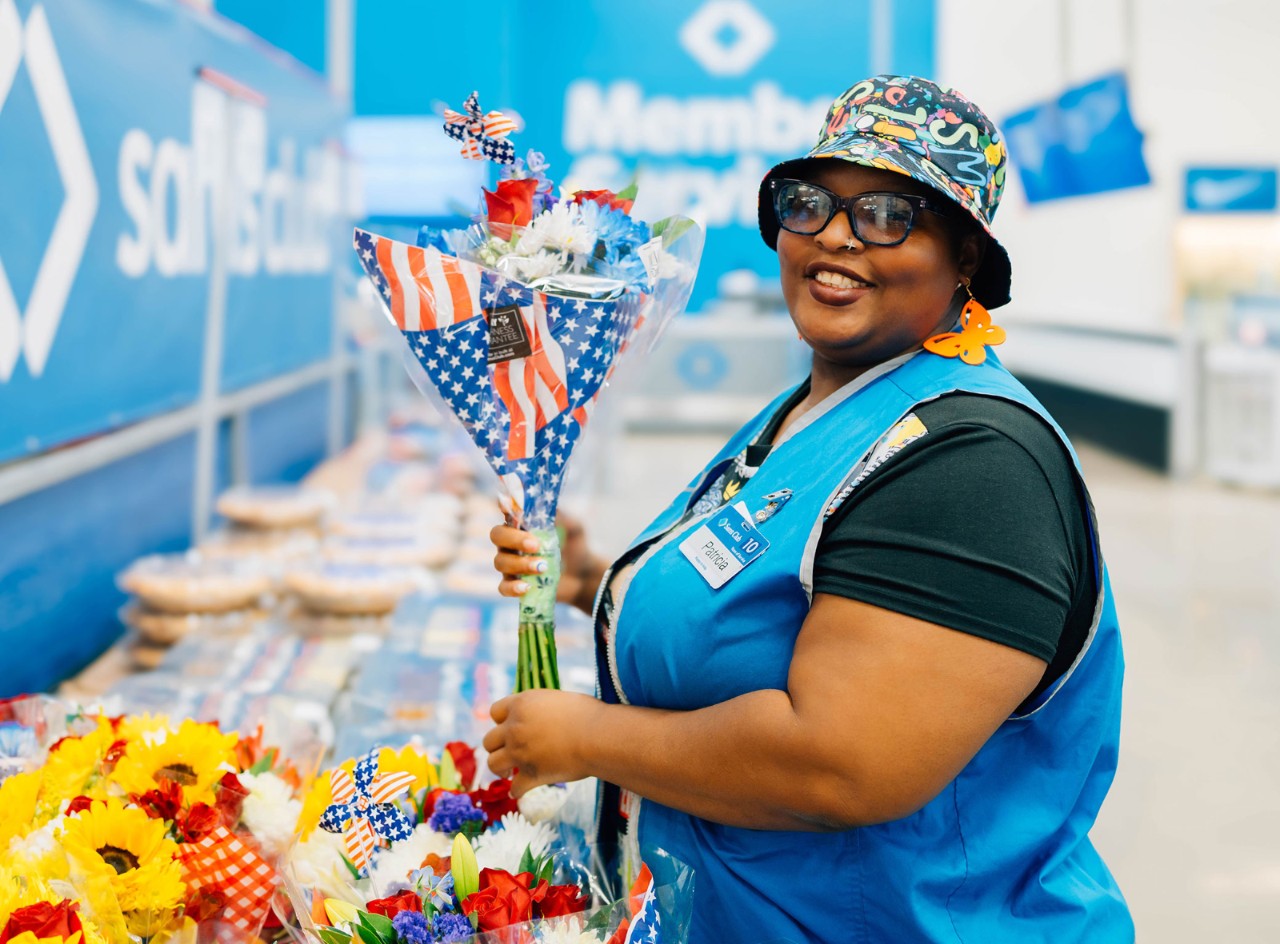 Sam’s Club associate Patricia Jackson holds a colorful bouquet of flowers and smiles.