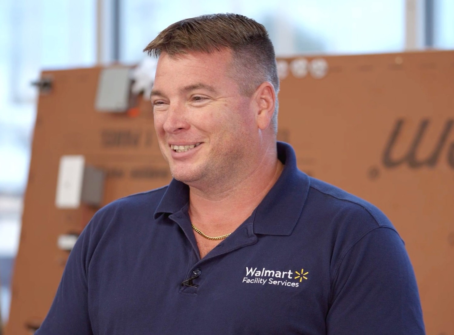 Veteran and Walmart associate Eric smiles as he wears a blue Walmart Facility Services uniform.