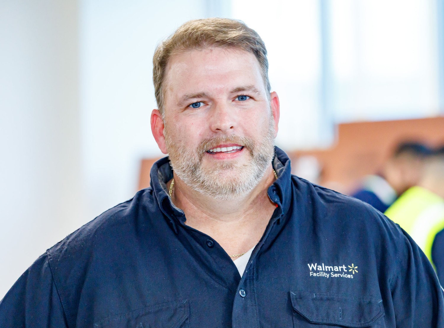 Jason smiles facing forward, wearing a blue Walmart Facility Services uniform during A2T classes.